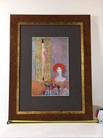 Framed print showing full frame and artwork with two women, one with red hair and one nude behind door, colorful glass goblets in front.