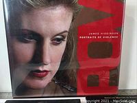 Close-up photo of a book cover showing a woman's face and title 'Portraits of Violence' by James Higginson.