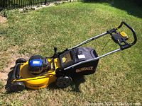 Side view of yellow steel deck, black grass bag with DeWalt logo and tubular handle