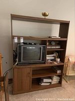 Full front view of the laminate media shelf with items like a TV and books on shelves showing overall design and condition.