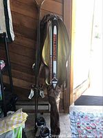 Two pairs of skis including Dynastar skis in travel case with poles and Yamaha skis, along with small vintage Nordica ski boots on floor beside them