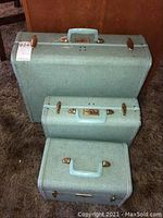 Photo of the 3-piece vintage Samsonite luggage set stacked on the carpet. Light blue textured exterior with brass hardware visible.