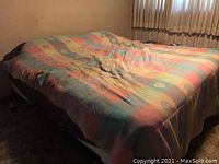 Photo of the king size bed covered with multicolored quilted blanket