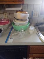 Image showing large plastic and metal bowls stacked along with white egg cups and a clear glass cruet multi-spouted bottle.