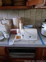 Rival electric grinder setup on counter with other kitchen items visible including baking dishes and a bowl.