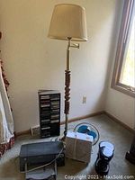 Full view of the floor lamp, fans, printer, coffee pot, and cassette rack in a room corner near window