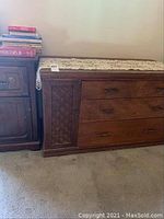 Full view of the wooden sideboard along a wall, showing three drawers and a side cabinet with lattice design.
