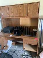 Oak-like laminate desk with cabinet hutch and vertical file organizers on desktop, showing wood grain finish and overall structure