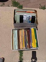 Two cardboard boxes filled with assorted hanging file folders and manilla files, arranged vertically.