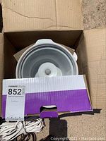 Rival slow cooker ceramic pot inside box showing part of electrical cord