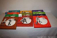 Wide shot showing all 14 boxed sets with colorful covers arranged on a table