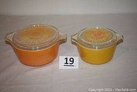 Two yellow Pyrex casserole dishes with glass lids featuring large sunflower design, shown from front