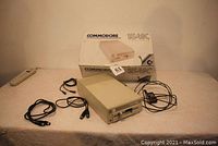 Photo of Commodore 1541C floppy disk drive with original box and cables on table.