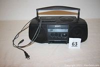 Front view of Sony Boombox CFD-V10 showing overall unit with power cord attached, carrying handle, and dual speakers.