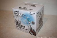 Front view of unopened Waterpik Water Flosser Complete Care 7.0 box showing product image and features.
