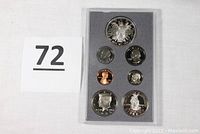 Front view of 7 coins in original proof set display, showing obverses including Kennedy, Liberty Dollar, and Statue of Freedom Half Dollar.