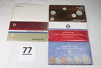 Five United States Mint original folders containing uncirculated coin sets from 1981, 1984, 1985, 1987, and 1991 displayed flat on a white surface.