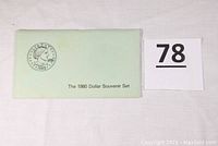 Green envelope labeled 'The 1980 Dollar Souvenir Set' with a 1980 coin illustration, indicating the packaging or accompanying holder for the coins.