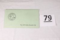 Pale green envelope labeled 'The 1979 Dollar Souvenir Set' shown flat on white surface alongside auction lot card number 79.
