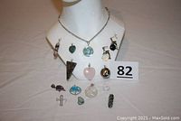 Full view of fifteen assorted gemstone pendants arranged on a display bust with a 30 inch silver chain necklace.