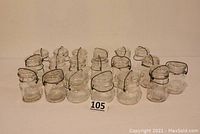 Lot of 19 clear pint-sized glass preserve/jelly jars with wire metal bands and glass lids, arranged on a table