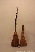 Photo showing both brooms side by side against a plain wall, displaying their length difference and handle styles.