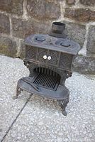 Front view of fully assembled stove showing ornate cast iron details and three-legged base.