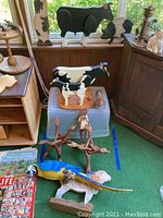 Full view of figurines including cow, rabbit, pig, bird, and parrot arranged around plastic bin.