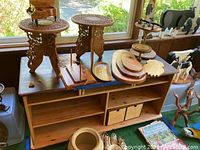 Overall view of wood storage stand with many wooden decor items on top including carved plant stands, platters, music box, ducks