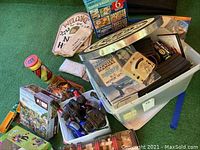 Overview of lot showing dartboard, puzzles including 1800 Super Value set, toy trucks and cars, and boxed Furby.