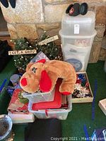 Full view of the lot showing stuffed dog, storage boxes, artificial trees with signs, Mickey Mouse ear hat, and assorted holiday decorations.