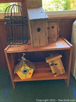 Full lot showing wooden side table with four wooden birdhouses on and under it, and metal decorative bird cage on the table.