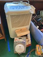 Maytag dehumidifier with front grille, towel ring, and Kidde carbon monoxide alarm displayed in front.