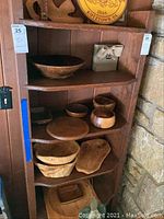 Full view of wood shelf tall with multiple shelves, showing nicks and scratches. Shelf contains wooden bowls and other items not included in sale.