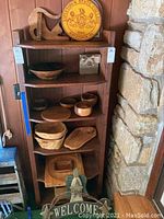 Wooden shelf displaying various wooden bowls, platters, wooden Welcome sign with angel, and Kutztown State College round sign.