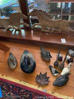 Photo of two wood horse figurines on a wooden surface near window with duck decoys and a carved leaf in front.