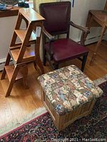 Wooden step ladder, wooden chair with burgundy cushion, and wooden storage ottoman with animal print upholstered seat, all shown together on hardwood floor with rug beneath.