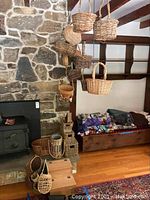 Photo showing wood step stool with multiple baskets on and around it, plus several baskets hanging by ropes from ceiling.