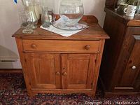Front view of wooden cabinet with drawer and two doors, showing top surface and door design.
