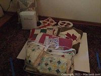 Photo showing several quilts and quilting fabric pieces folded and stacked on the floor.