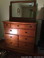 Full view of wood dresser with nine drawers and matching wood-framed mirror on top.