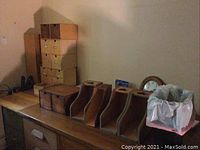 Wooden storage cubes stacked, wooden file organizers, wall clock partially visible, trash bin