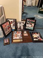 Photo showing multiple framed sports images and plaques featuring Mark Messier, displayed on carpeted floor.