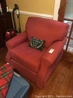 Full view of the red Hickory Hill arm chair in a room with hardwood floors and adjacent furniture.