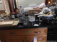 Wide view showing multiple kitchen gadgets on a countertop, including metal colanders, plastic peelers, strainers, coffee carafe, and utensils.