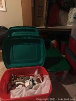 Green and red plastic storage bins containing Christmas decorations, showing general lot setup.