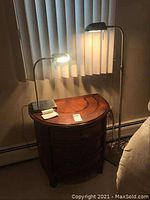 Photo showing floor lamp and table lamp both turned on beside wooden side table near window blinds.