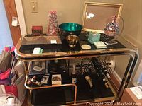 Two-tier console table with various religious and decorative items arranged on top and lower shelf.