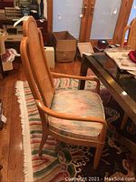 Single captain chair side view showing curved armrest, veneer back panel and upholstered seat.