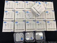 Fifteen HUAYT Premium Headset Earphones boxes with three sets in clear plastic opened cases visible on a black surface.